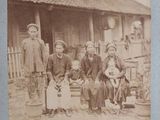 an old photo of a group of people sitting in front of a house