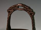 a small metal basket with a handle on a table