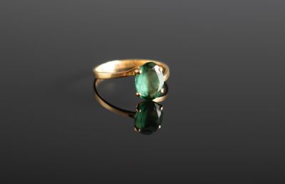gros plan d'une bague en or avec une pierre verte