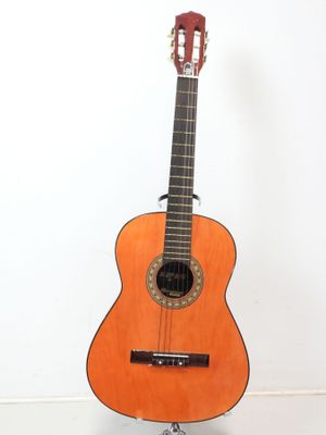 une guitare acoustique posée sur un support, adossée à un mur blanc