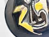 a black plate with a yellow and white painting on it