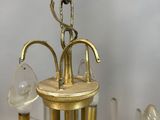 a gold chandelier with a glass shade hanging from it