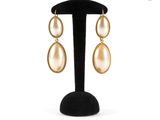 a pair of gold earrings with pearls on a black stand