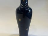 blue vase with gold stars on it sitting on a white surface