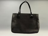 black leather tote bag hanging from a hook on a wall