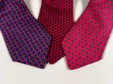 three different colored ties on a white surface with one red and the other blue