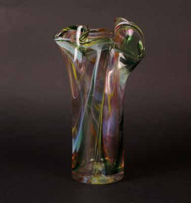 a clear glass vase with multi colored swirls on a black background