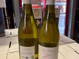 two bottles of white wine sitting on a table