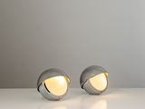 two silver lamps sitting on top of a white table next to each other