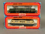 deux boîtes contenant des trains miniatures Märklin posées sur une surface grise