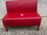 un banc rouge posé sur le trottoir