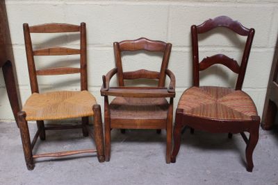 trois chaises en bois placées les unes à côté des autres devant un mur de briques blanches