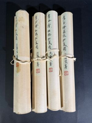 quatre livres enroulés, portant des inscriptions en chinois, posés sur une table