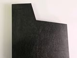 a close up of a piece of black paper on a white surface