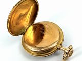 a gold pocket watch sitting on a white surface