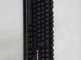 a black keyboard on a white wall with a sticker on it