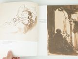 a person holding a book open to a drawing of a woman