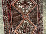 Un vieux tapis orné d'un motif en forme de croix est accroché au mur.