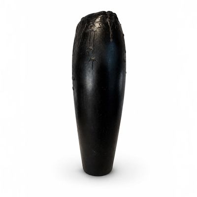 un vase noir posé sur une surface blanche