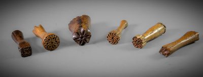 six pièces de bois sculpté sont disposées en rangée sur une surface grise