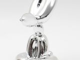 a silver sculpture of a bird sitting on top of a plate