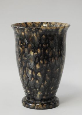 un vase noir et doré posé sur une table blanche