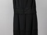 a black dress hanging on a hanger against a white wall