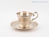 une tasse et une soucoupe anciennes en argent, posées sur une soucoupe
