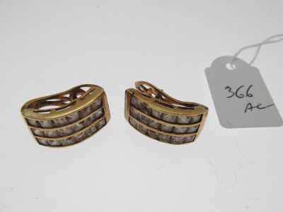 une paire de boucles d'oreilles dorées ornées de pierres blanches et d'une étiquette de prix