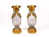 une paire de vases en or et en verre transparent posés sur un socle en bois