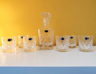 six glasses and a decanter sitting on a table