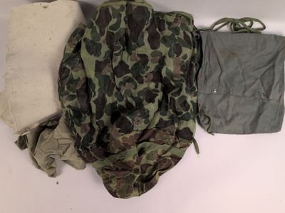 un sac à dos camouflage et un pantalon posés sur une surface blanche