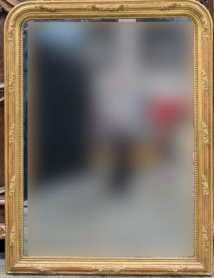 un miroir à cadre doré posé sur une table à côté d'une horloge