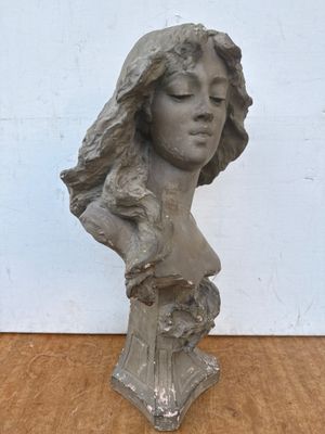 sculpture représentant la tête d'une femme aux longs cheveux, posée sur une table en bois