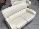 a white leather couch and a recliner in a garage