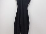 the black jumpsuit is hanging on a hanger against a white wall