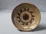 une assiette marron et rouge posée sur un support, sur une table