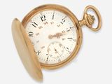 une montre de poche en or posée sur une surface blanche