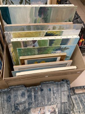 beaucoup de tableaux dans une boîte posée par terre