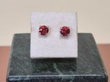 a pair of red earrings sitting on top of a marble block