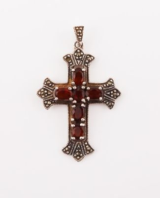 une croix en argent ornée de pierres rouges sur fond blanc