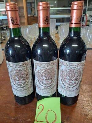 trois bouteilles de vin posées sur une table en bois, à côté d'une étiquette de prix