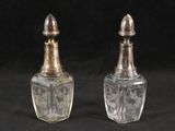 une paire de salières et poivrières anciennes en verre sur fond noir