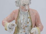 a figurine of a man in a pink jacket and white pants