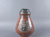 a red vase with a black lid sitting on a table