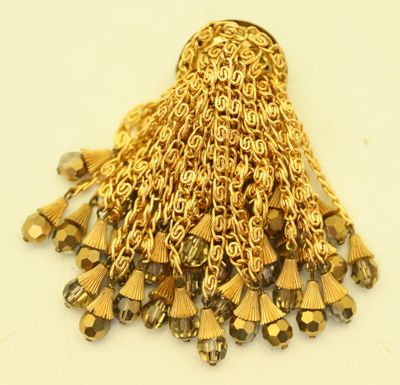 a close up of a gold chain tassel on a white surface