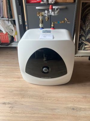 un chauffe-eau posé par terre devant une bibliothèque