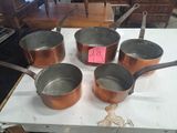 plusieurs casseroles et poêles posées sur une table, avec une étiquette de prix