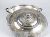 silver plated serving dish with lid and handles on a white surface