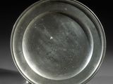 une assiette en argent posée sur une surface blanche avec un fond noir
